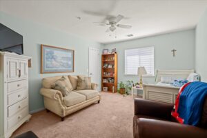 Bright resident room with a sofa, ceiling fan, and care bed beside a window