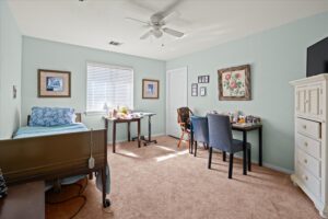 Resident bedroom with a care bed, small dining table, and armchairs