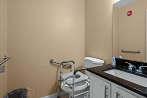Accessible bathroom featuring a curbless walk-in shower, grab bars, and a mobility walker