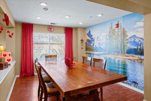 Dining room with a long wooden table beneath a mountain-and-lake wall mural