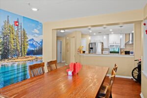Open dining area with a scenic wall mural and wood table connecting to the kitchen