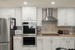 Modern kitchen with stainless steel appliances, white cabinetry, and a tile backsplash