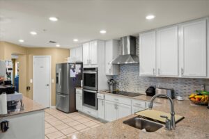 Kitchen with a stainless steel refrigerator, white cabinetry, and granite counters