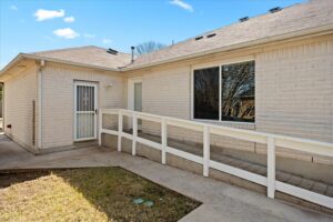 Back exterior of the home with a wheelchair-accessible ramp and concrete patio