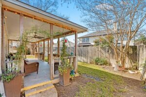 Landscaped backyard with a covered patio, outdoor seating, and garden beds