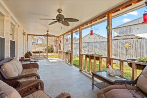 Covered back patio with a ceiling fan and wicker lounge furniture