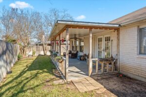 Covered back porch overlooking the fenced backyard and lawn